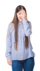 Young Chinese woman over isolated background covering one eye with hand with confident smile on face and surprise emotion.