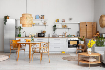 Interior of light kitchen with stylish fridge, counters, shelves, table and chairs