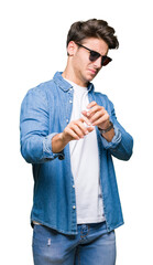 Young handsome man wearing sunglasses over isolated background disgusted expression, displeased and fearful doing disgust face because aversion reaction. With hands raised. Annoying concept.