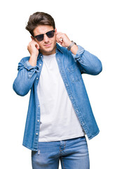 Young handsome man wearing sunglasses over isolated background covering ears with fingers with annoyed expression for the noise of loud music. Deaf concept.