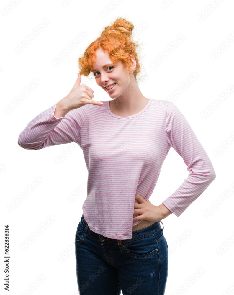 Wall mural Young redhead woman smiling doing phone gesture with hand and fingers like talking on the telephone. Communicating concepts.