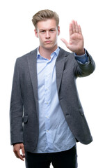 Young handsome blond business man doing stop sing with palm of the hand. Warning expression with negative and serious gesture on the face.