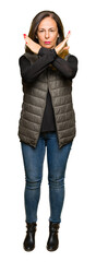 Obraz premium Beautiful middle age woman wearing winter vest Rejection expression crossing arms doing negative sign, angry face