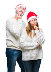 Middle age hispanic couple wearing christmas hat over isolated background with hand on chin thinking about question, pensive expression. Smiling with thoughtful face. Doubt concept.