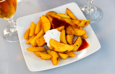 Delicious baked potatoes with spicy creamy sauce aioli and tomato salsa. Popular Spanish dish Patatas bravas..