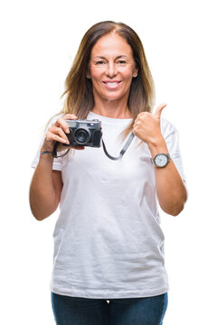 Middle age hispanic woman taking pictures using vintage photo camera over isolated background happy with big smile doing ok sign, thumb up with fingers, excellent sign