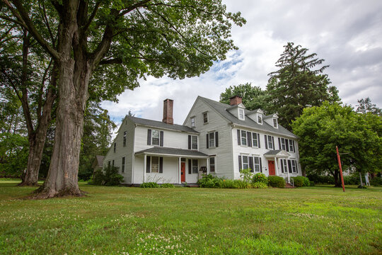 Large white New England style historical colonial home with bump out and green lawn in Cheshire Connecticut