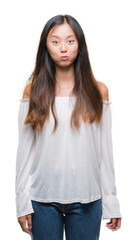 Young asian woman over isolated background puffing cheeks with funny face. Mouth inflated with air, crazy expression.
