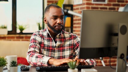 Employee concentrating on finishing up important job tasks, remotely working from stylish apartment...