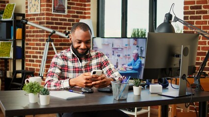 Relaxed african american man scrolling on his phone entertained by social media activity. Happy...