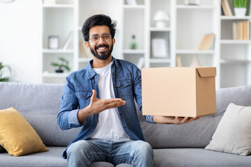 Handsome Smiling Indian Man Pointing At Cardboard Box With Delivery At Home