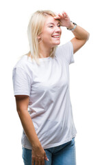 Young beautiful blonde woman wearing white t-shirt over isolated background very happy and smiling looking far away with hand over head. Searching concept.