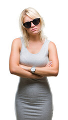Young beautiful blonde woman wearing sunglasses over isolated background skeptic and nervous, disapproving expression on face with crossed arms. Negative person.