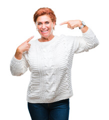 Atrractive senior caucasian redhead woman wearing winter sweater over isolated background smiling confident showing and pointing with fingers teeth and mouth. Health concept.
