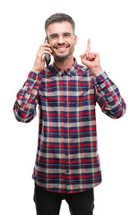 Fototapeta premium Young hipster adult man talking on the phone surprised with an idea or question pointing finger with happy face, number one