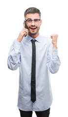 Young business adult man talking on the phone screaming proud and celebrating victory and success very excited, cheering emotion