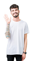 Young handsome man wearing white t-shirt over isolated background Waiving saying hello happy and smiling, friendly welcome gesture