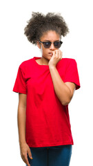 Young afro american woman wearing sunglasses over isolated background looking stressed and nervous with hands on mouth biting nails. Anxiety problem.