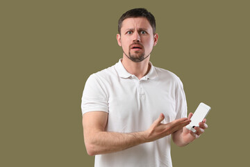 Shocked man with smartphone on color background