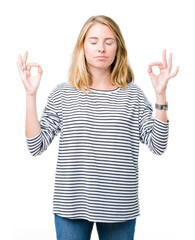 Fototapeta na wymiar Beautiful young woman wearing stripes sweater over isolated background relax and smiling with eyes closed doing meditation gesture with fingers. Yoga concept.