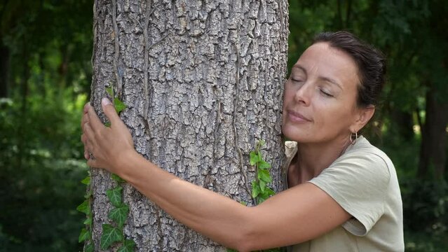 Lady care tree hugs in summer wood. A young lady embrace with love the tree in the green botany park in summer. A concept of Earth day celebration and no pollution movement.