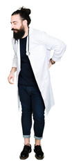 Doctor with long hair wearing medical coat and stethoscope Suffering of backache, touching back with hand, muscular pain