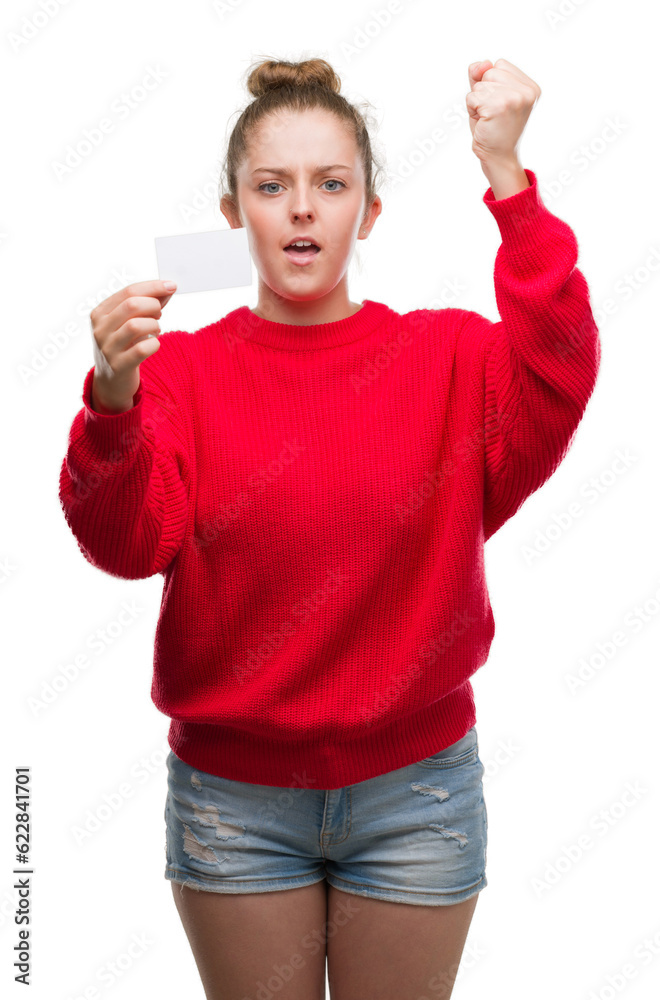 Wall mural young blonde woman holding advertising card annoyed and frustrated shouting with anger, crazy and ye