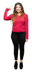 Young beautiful woman wearing red sweater Smiling pointing to head with one finger, great idea or thought, good memory