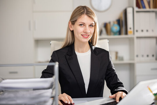 Young woman bookkeeper working in her workplace in office and looking at camera.