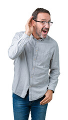 Handsome middle age elegant senior man wearing glasses over isolated background smiling with hand over ear listening an hearing to rumor or gossip. Deafness concept.