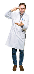 Fototapeta premium Middle age doctor men wearing medical coat gesturing with hands showing big and large size sign, measure symbol. Smiling looking at the camera. Measuring concept.