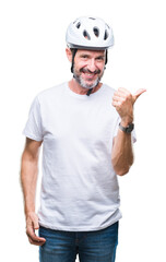 Middle age senior hoary cyclist man wearing bike safety helment isolated background smiling with happy face looking and pointing to the side with thumb up.