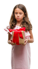 Fototapeta premium Brunette hispanic girl holding a gift with a confident expression on smart face thinking serious