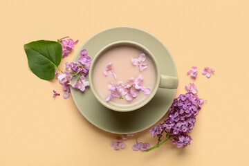 Cup of coffee and beautiful lilac flowers on beige background