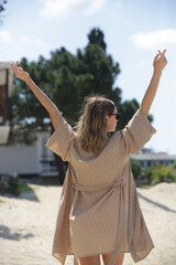Woman on the beach with raised arms during hot summer day. Concept of freedom, happiness and positivity.