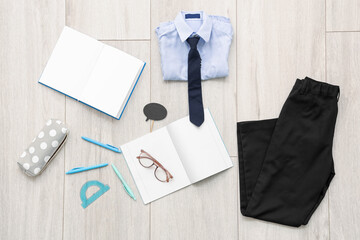 Composition with stylish school uniform, eyeglasses and stationery on wooden background