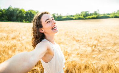 Happy woman with arms outstretched enjoying freedom in a wheat field - Joyful female breathing fresh air outside - Healthy life style, happiness and mental health concept