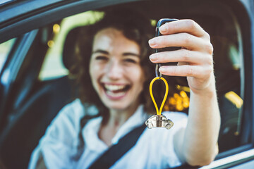 Happy woman buying new car - Delightful girl showing auto keys to the camera - Automobile industry...