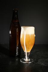 Bottle and glass of cold beer on dark background