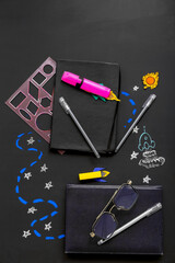 Creative composition with rockets, eyeglasses and different stationery on black chalkboard
