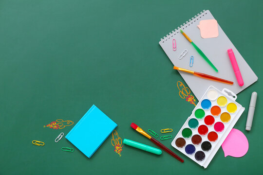Creative composition with drawn rockets and different stationery on green chalkboard