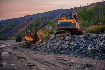 Excavators and dump trucks working on earthmoving at open pit mine in mining and processing plant