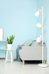 Interior of living room with sofa, houseplant, lamp and table