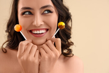 Young woman with lollipops on beige background, closeup