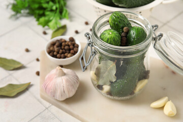 Jar with fresh cucumbers for preservation on white tile background