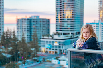 Fototapeta na wymiar Boy standing on balcony admiring the view from a highrise apartment in Surfers Paradise on the Gold Coast, Queensland Australia