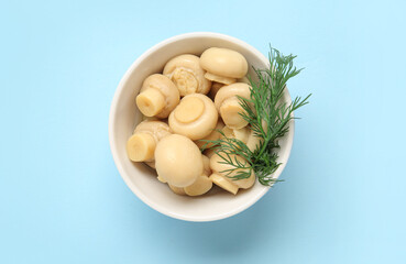 Bowl with canned mushrooms on blue background