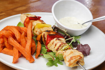 Greek souvlaki, sweet potatoe and tzatziki yogurt dip served on the plate in the restaurant	