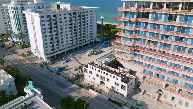 Picturesque seaside resort with row of hotel complexes near sandy beach of Miami. Drone view on construction site of multi-storey apartment building with amazing ocean scenery
