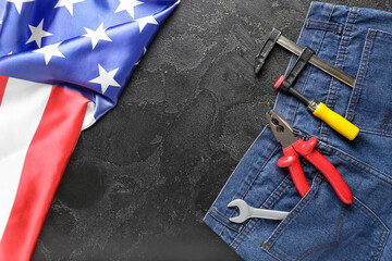 Composition with jeans, different tools and USA flag on black background. Labor Day celebration
